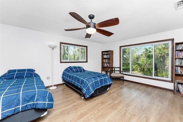 bedroom with wood-type flooring, multiple windows, and ceiling fan