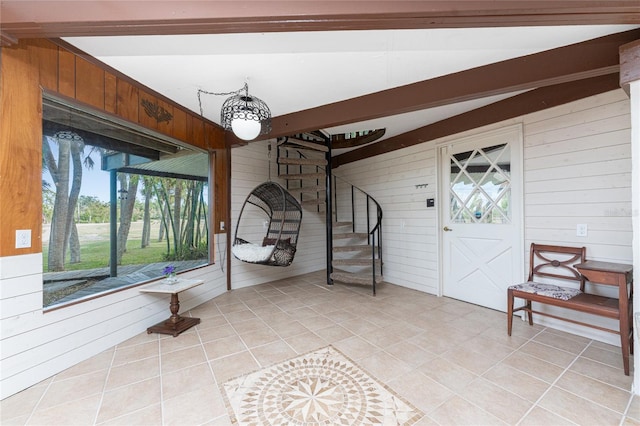 foyer featuring wooden walls, light tile patterned floors, and lofted ceiling with beams