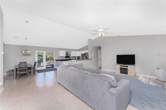 tiled living room with ceiling fan with notable chandelier and lofted ceiling