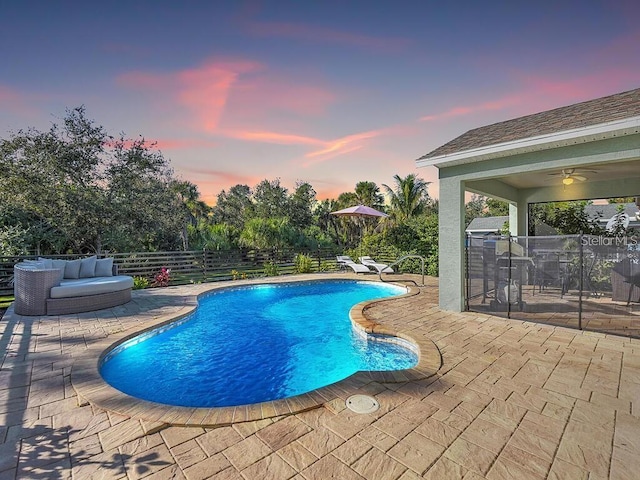 pool at dusk with ceiling fan and a patio