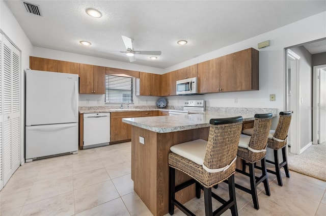 kitchen featuring a textured ceiling, a breakfast bar, white appliances, and sink