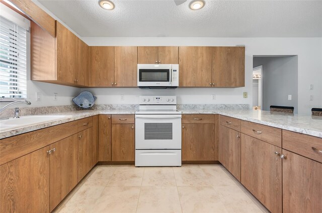 kitchen with electric stove, sink, light tile patterned floors, and a textured ceiling