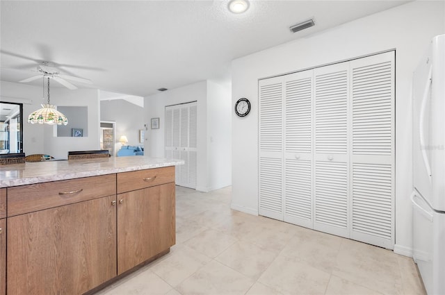 kitchen with ceiling fan, white fridge, a textured ceiling, and decorative light fixtures