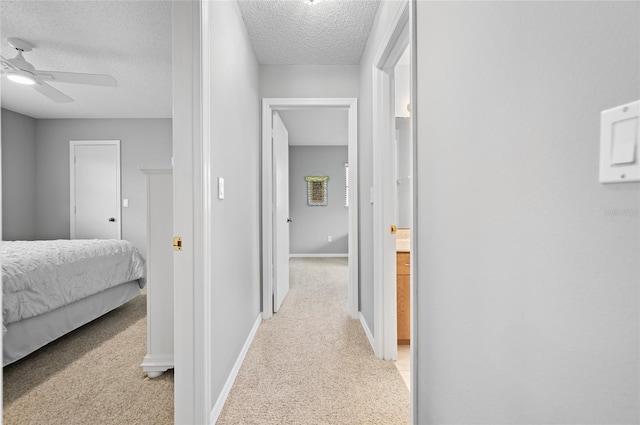 hallway with light carpet and a textured ceiling