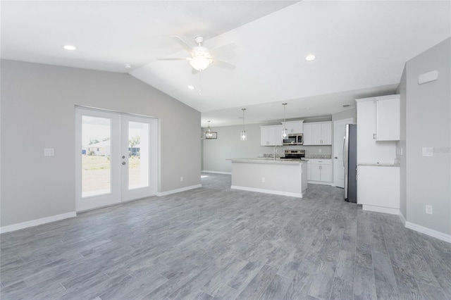 unfurnished living room with french doors, ceiling fan, sink, light hardwood / wood-style floors, and lofted ceiling