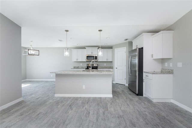 kitchen featuring white cabinets, stainless steel appliances, decorative light fixtures, and light hardwood / wood-style floors