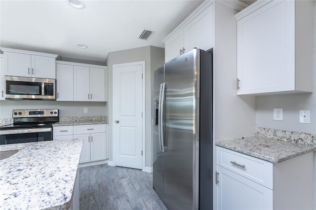 kitchen with white cabinets, dark hardwood / wood-style floors, light stone countertops, and appliances with stainless steel finishes