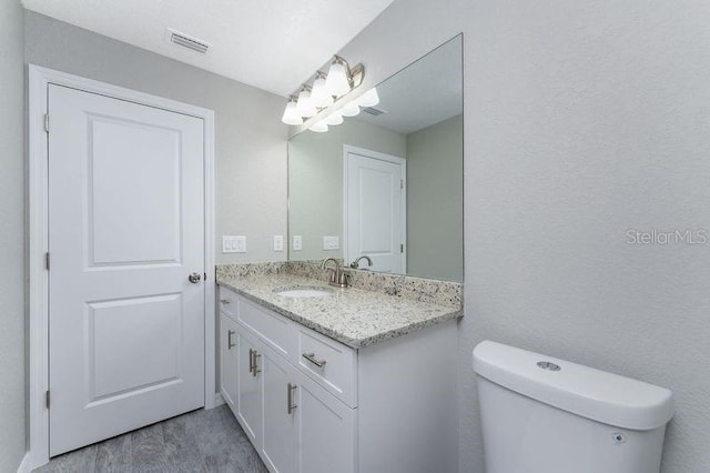 bathroom featuring vanity, hardwood / wood-style flooring, and toilet