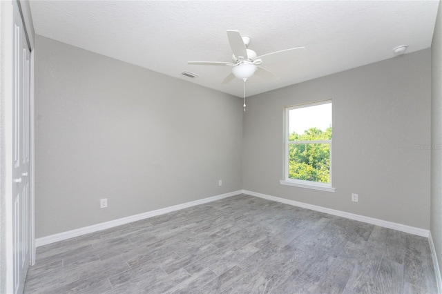 empty room with a textured ceiling, light hardwood / wood-style floors, and ceiling fan