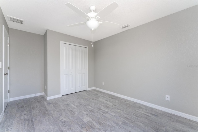 unfurnished bedroom featuring light hardwood / wood-style flooring, a closet, and ceiling fan