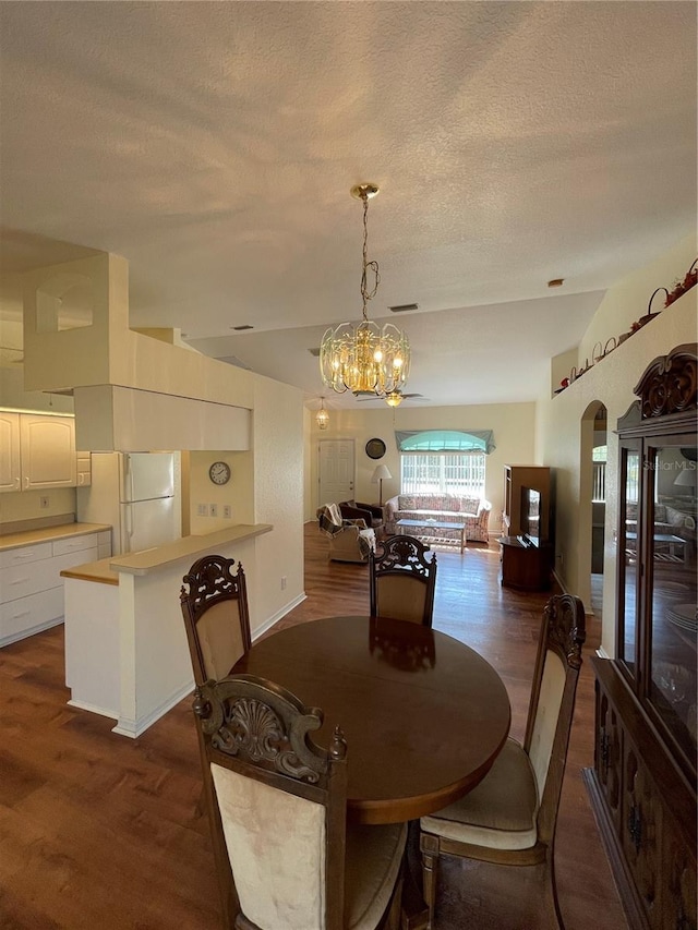 dining room with dark wood-type flooring and an inviting chandelier