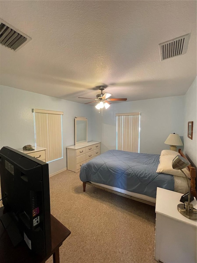 carpeted bedroom featuring ceiling fan and a textured ceiling