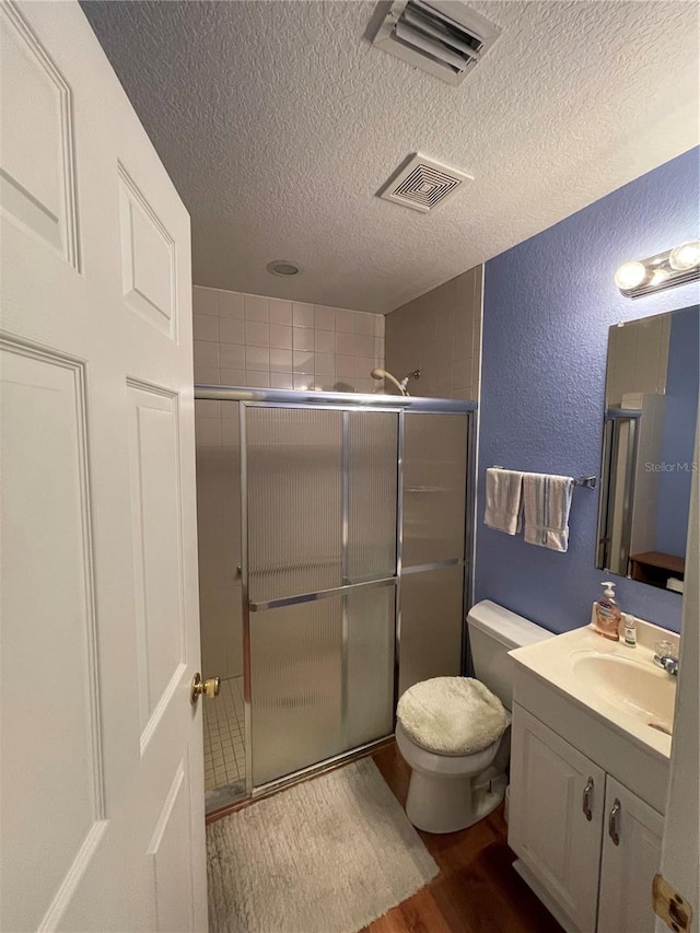 bathroom with toilet, vanity, wood-type flooring, and a shower with door