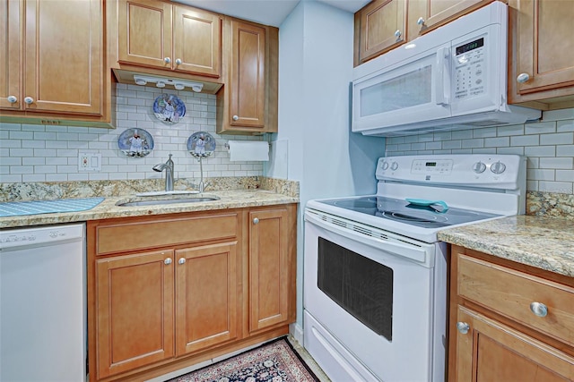 kitchen featuring decorative backsplash, light stone counters, white appliances, and sink