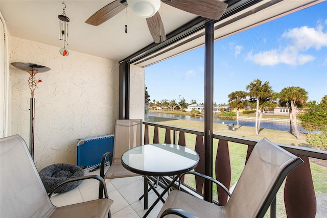 sunroom with ceiling fan and a water view