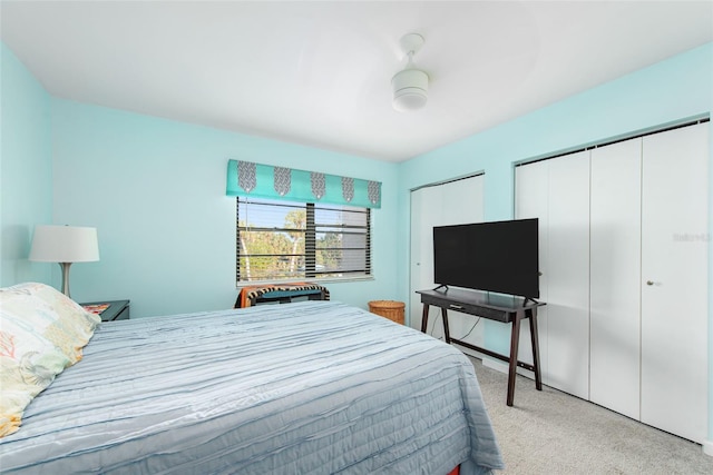 carpeted bedroom with ceiling fan and two closets