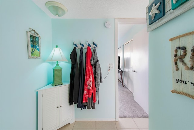 hallway with light carpet and a textured ceiling