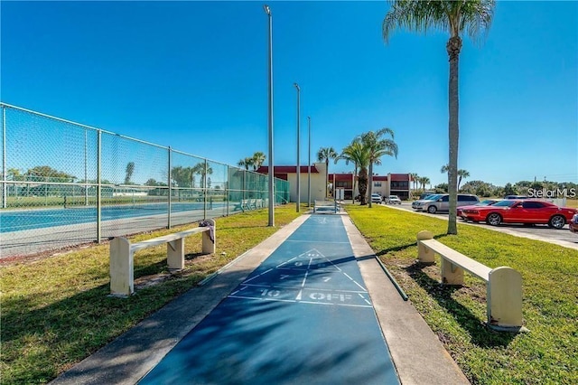 view of property's community featuring a lawn and tennis court