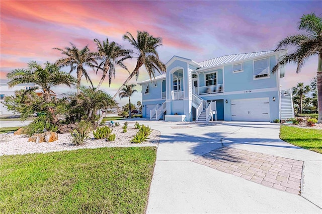 13104 Via Cassia, Placida, FL 33946 - raised beach house with stairs, a garage, stucco siding, driveway, and a standing seam roof