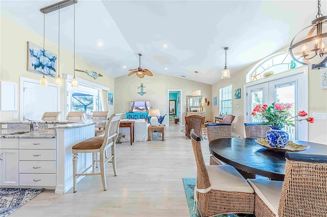 dining room featuring french doors, lofted ceiling, light hardwood / wood-style floors, sink, and ceiling fan with notable chandelier