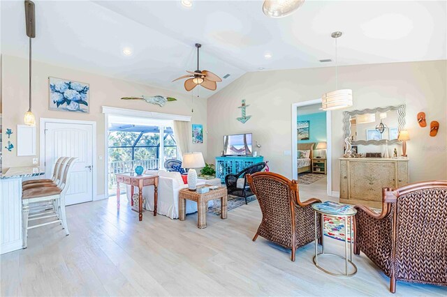 living room with ceiling fan, light hardwood / wood-style floors, and vaulted ceiling