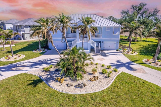 13104 Via Cassia, Placida, FL 33946 - coastal inspired home featuring driveway, stairway, a garage, stucco siding, and a porch
