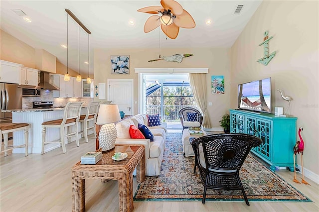 living room with light hardwood / wood-style floors, lofted ceiling, and ceiling fan