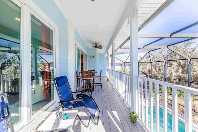 deck featuring ceiling fan, glass enclosure, and a patio area