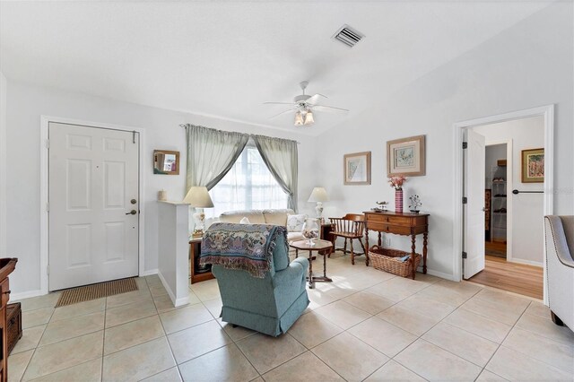 living room featuring ceiling fan, light tile patterned floors, and lofted ceiling