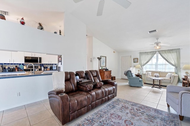 tiled living room with ceiling fan, sink, and high vaulted ceiling