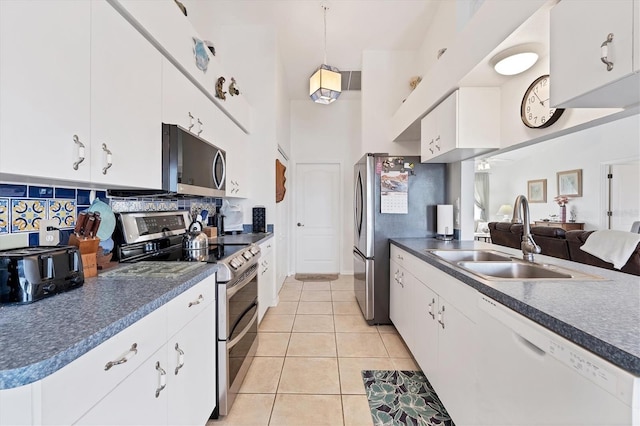 kitchen featuring appliances with stainless steel finishes, sink, light tile patterned floors, decorative light fixtures, and white cabinets