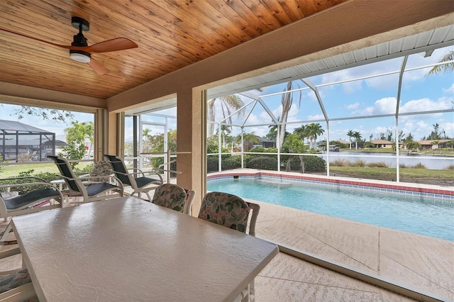 view of pool featuring a water view, glass enclosure, and ceiling fan