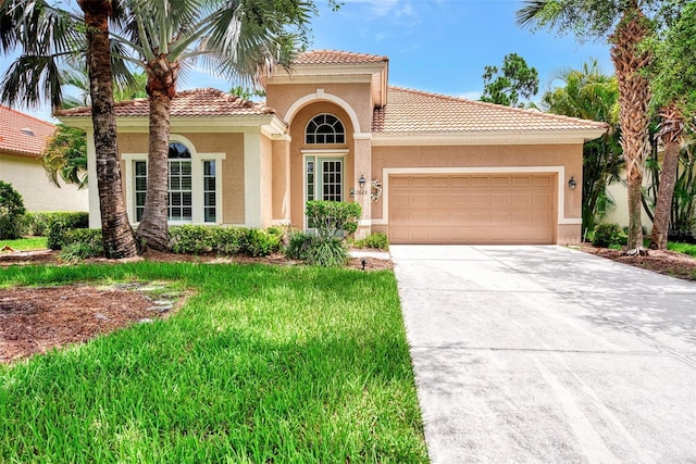 mediterranean / spanish home with a garage and a front lawn