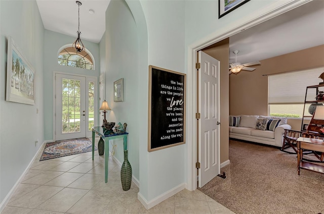 carpeted foyer entrance featuring ceiling fan, a towering ceiling, and a wealth of natural light