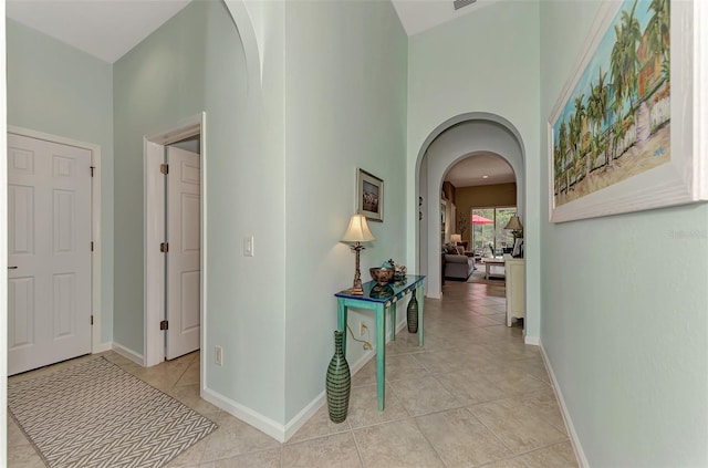 hall featuring light tile patterned floors and a high ceiling