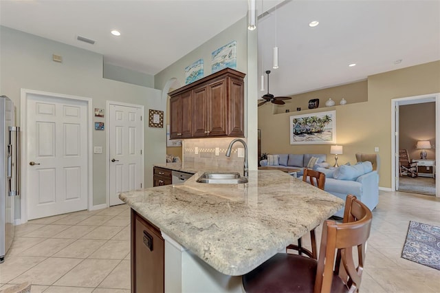 kitchen with kitchen peninsula, tasteful backsplash, a breakfast bar, ceiling fan, and sink