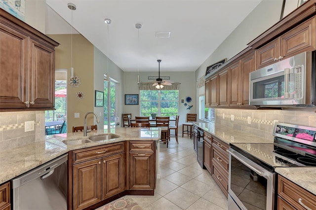 kitchen with tasteful backsplash, stainless steel appliances, ceiling fan, sink, and hanging light fixtures