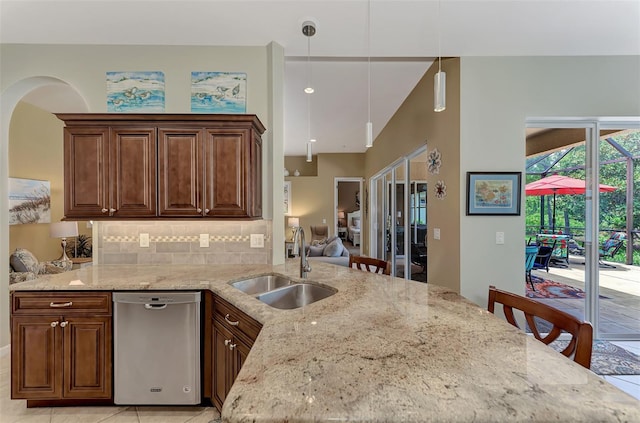 kitchen featuring sink, stainless steel dishwasher, decorative light fixtures, a kitchen bar, and kitchen peninsula