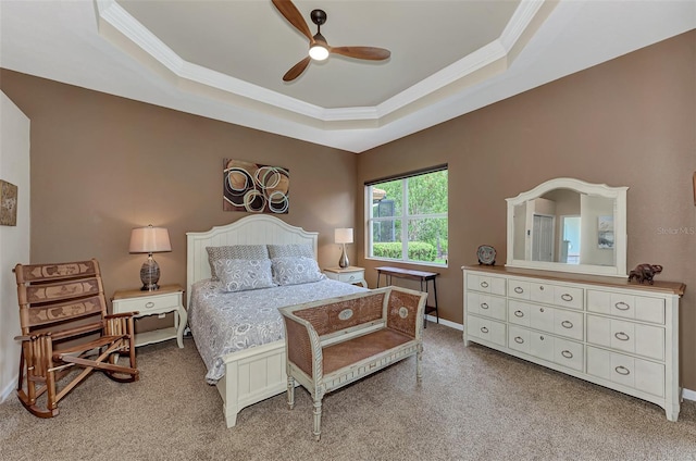 carpeted bedroom with a raised ceiling, ceiling fan, and crown molding