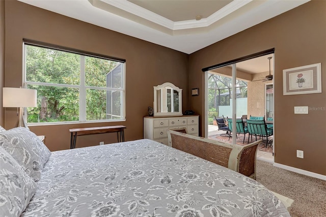 carpeted bedroom with crown molding, a tray ceiling, and multiple windows