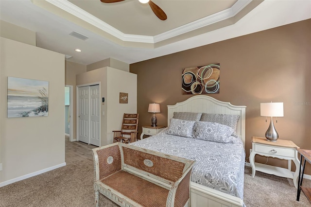 carpeted bedroom featuring ceiling fan, a closet, crown molding, and a tray ceiling