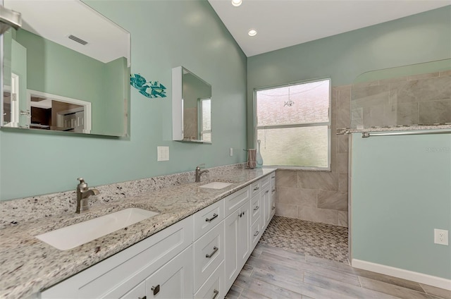 bathroom with hardwood / wood-style floors, vanity, and a tile shower