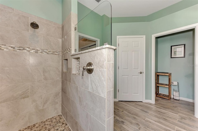 bathroom with hardwood / wood-style floors and a tile shower