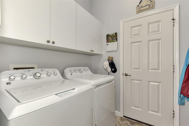 clothes washing area featuring cabinets and washer and clothes dryer