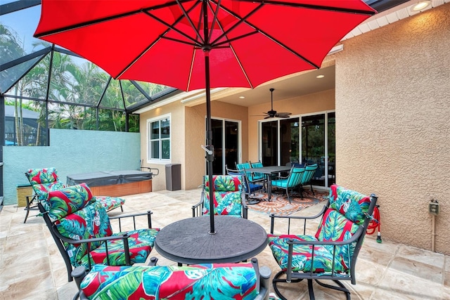 view of patio featuring glass enclosure, a hot tub, and ceiling fan