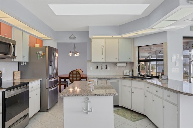 kitchen with appliances with stainless steel finishes, white cabinetry, a kitchen island, and sink