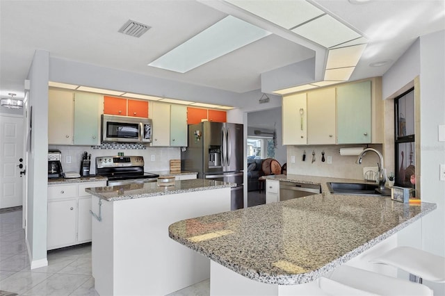 kitchen featuring sink, decorative backsplash, a kitchen bar, kitchen peninsula, and stainless steel appliances