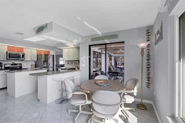 kitchen featuring stone countertops, a kitchen island, appliances with stainless steel finishes, and tasteful backsplash