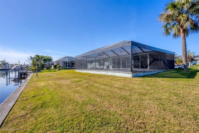 view of yard with glass enclosure, a water view, and a boat dock