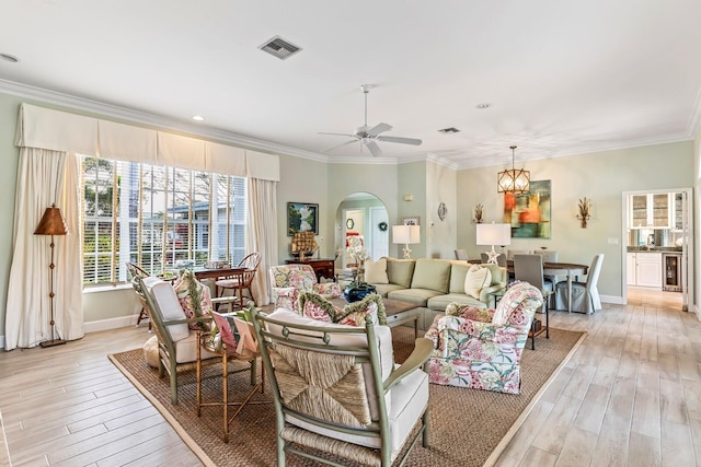 living room with ceiling fan with notable chandelier, ornamental molding, beverage cooler, and light hardwood / wood-style flooring